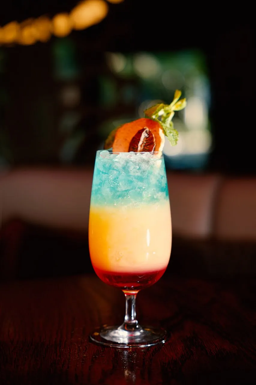 A blue tropical cocktail with citrus and mint garnish