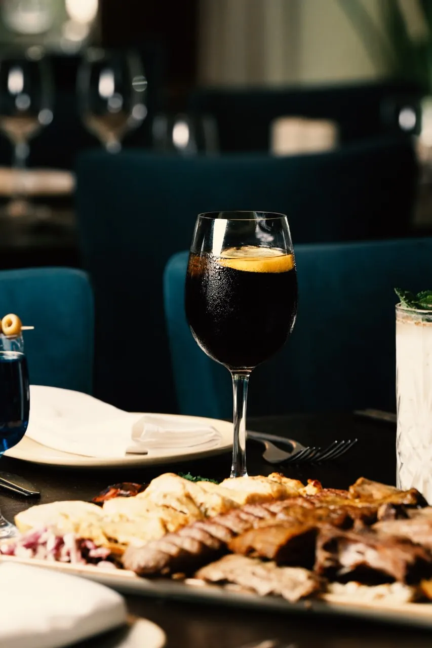 A grilled sharing platter served beside a dark drink