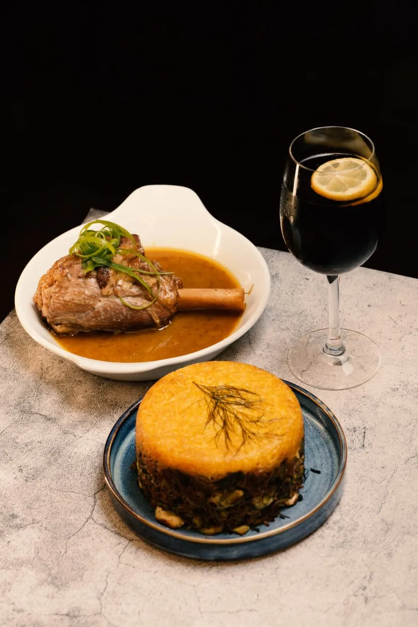 Lamb shank, saffron tahdig and a dark drink served together