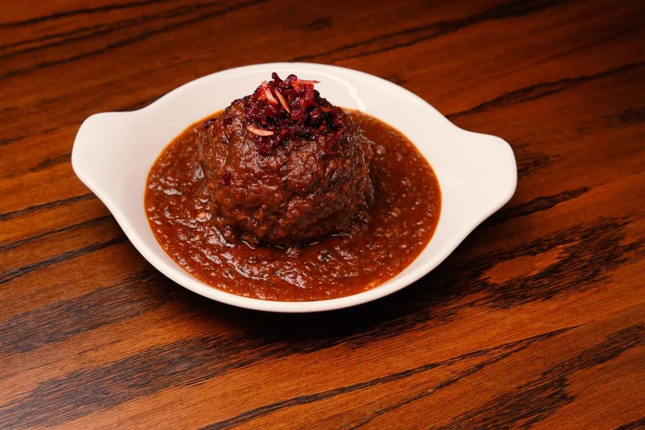 A Persian meatball in rich tomato sauce on a wooden table