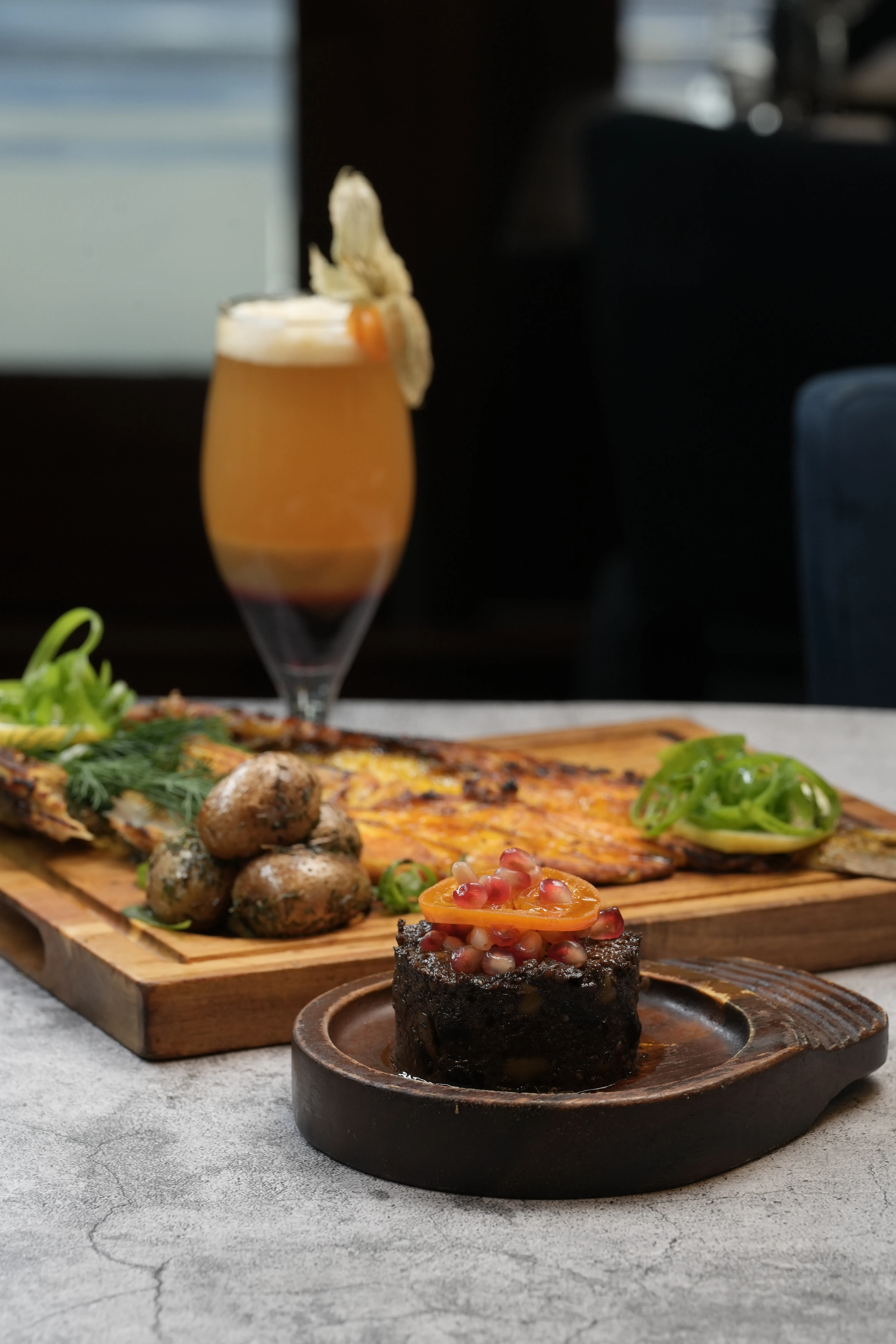 A Persian grilled fish platter with herbed potatoes, pomegranate garnish and a cocktail