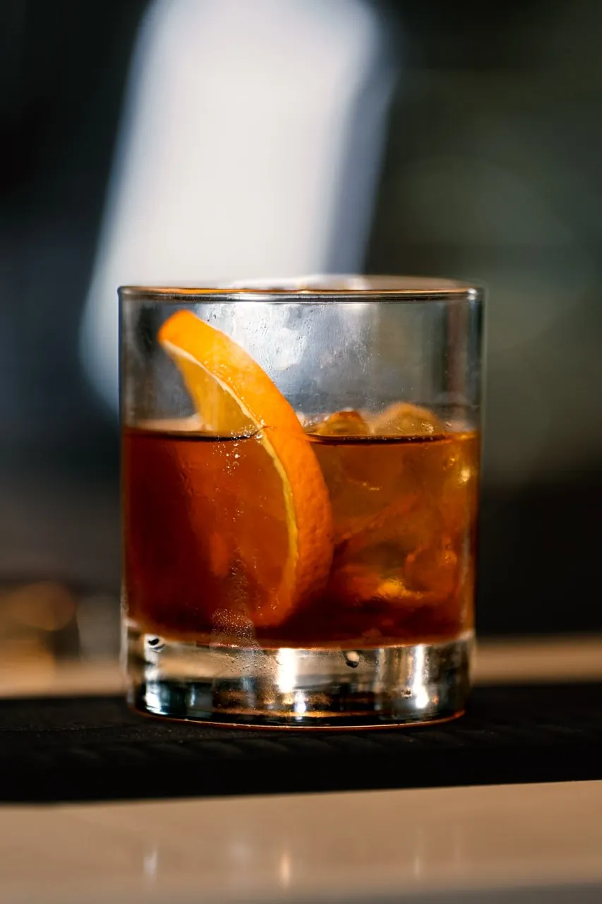 An old fashioned cocktail served with an orange garnish
