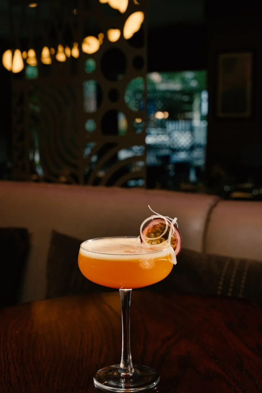 An orange passionfruit cocktail garnished with fresh fruit