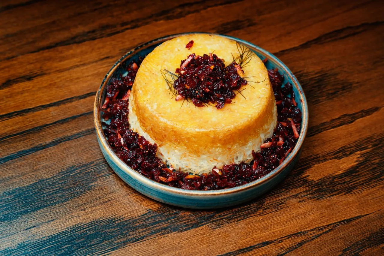 Saffron tahdig served with barberries on a blue plate