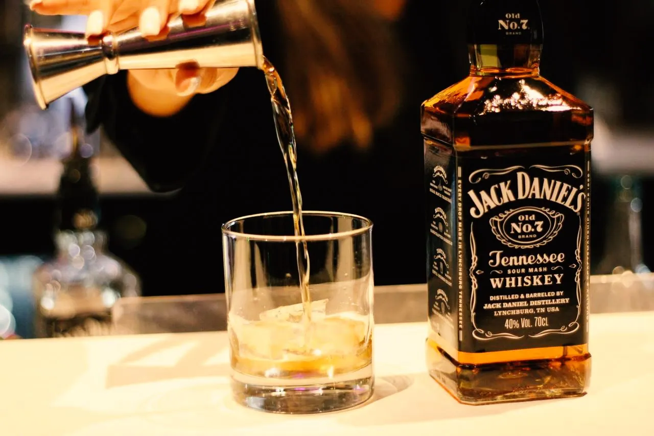 Whiskey being poured beside a Jack Daniel's bottle